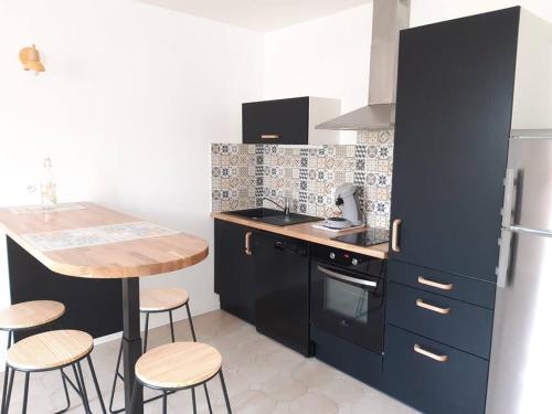 a kitchen with black cabinets and a table and stools at charmante maison de ville toute équipée in Châteauroux