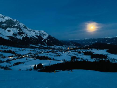 a full moon rising over a snow covered mountain at Bergkristallhaus in Ramsau am Dachstein