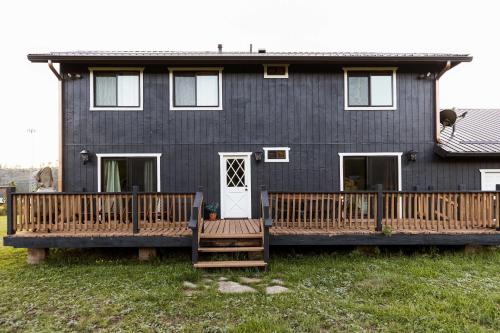 a black house with a porch and a deck at Whispering Hollow Lodge on Greer Main St! in Greer