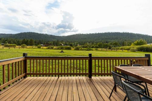a wooden deck with a table and chairs and a field at Whispering Hollow Lodge on Greer Main St! in Greer