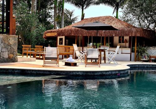 un complejo con mesa, sillas y piscina en Taman Búzios Hotel, en Búzios