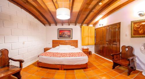 a bedroom with a bed and two chairs at El Camino de Maia in Tlayacapan