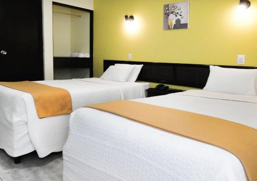 a hotel room with two beds and a mirror at Hotel Plaza in Tacna