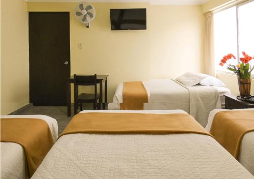 a hotel room with three beds and a window at Hotel Plaza in Tacna