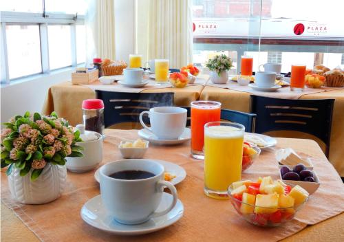 a table topped with cups of coffee and fruit at Hotel Plaza in Tacna