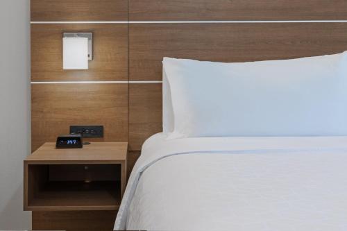 a bedroom with a bed and a alarm clock on a table at Holiday Inn Express & Suites - Denton - Sanger by IHG in Sanger