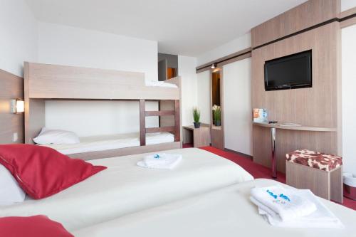 a hotel room with two beds and a flat screen tv at Hôtel Club mmv Les Mélèzes **** in Arc 2000