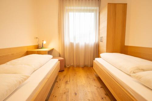 three beds in a room with a window at Lahnhof in Lana