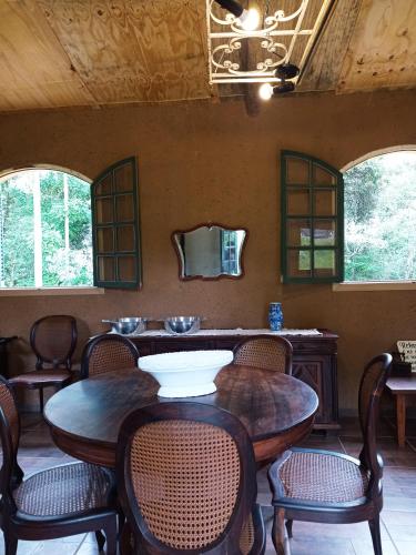 a dining room with tables and chairs and windows at Pousada Sitio da Terra e Arte in São Roque