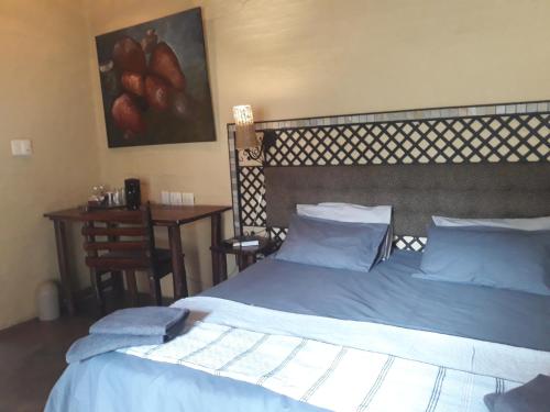 a bedroom with two beds and a table with a painting at African Silhouette Guesthouse in Benoni