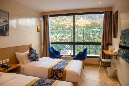 a hotel room with two beds and a large window at VANCII Hotel in Chefchaouen