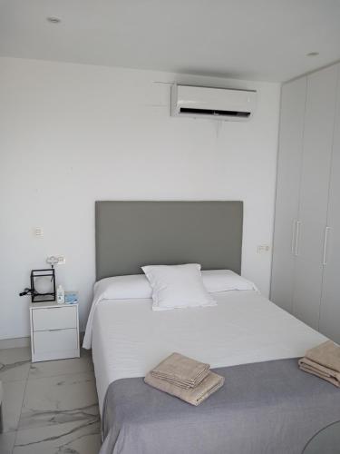 a white bedroom with a bed and a tv at Coqueto estudio-ático EN PRIMERA LÍNEA DE PLAYA CON PRECIOSAS VISTAS AL MAR in Almería