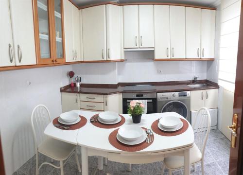 a white kitchen with a white table and chairs at Arrantzale Beach in Bermeo