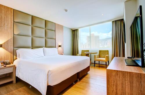 メデジンにあるHotel San Fernando Plazaの大きなベッドと窓が備わるホテルルームです。