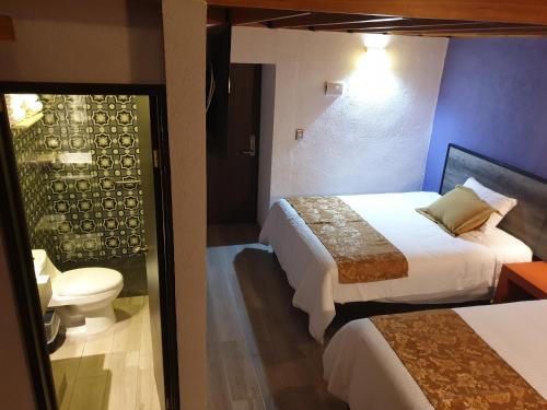 a hotel room with two beds and a toilet at Hotel Don Carlos in Morelia