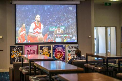 a large projection screen in a room with tables at Nightcap at St Albans Hotel in St Albans