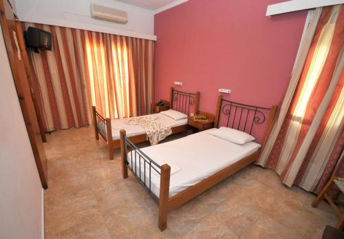 two beds in a room with red walls at Hotel Galaxy in Souvala