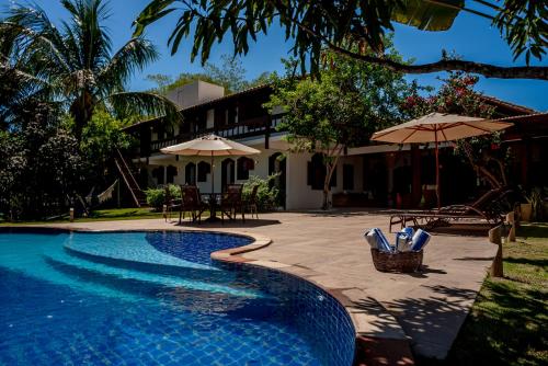 uma piscina com guarda-sóis e uma casa em Casa da Vila Outeiro das Brisas em Praia do Espelho