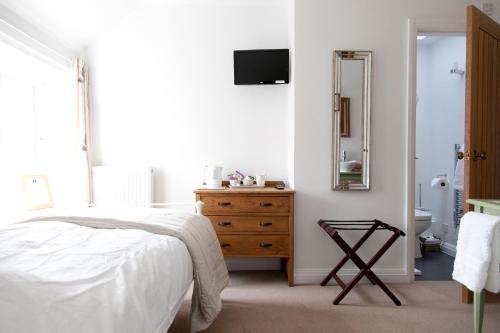 a bedroom with a bed and a dresser and a mirror at Belmont Bed and Breakfast in Pickering