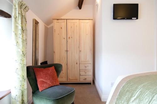 a bedroom with a bed and a chair and a television at Belmont Bed and Breakfast in Pickering