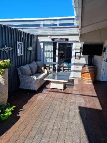 a patio with a couch and a tv on a house at BnB on Carvell in Blenheim