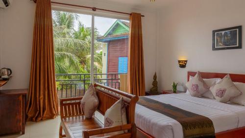 a bedroom with a bed and a large window at La Villa du Bonheur in Siem Reap