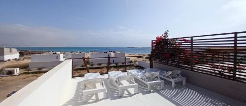 uma varanda com cadeiras brancas e vista para o oceano em KatlantiK Ca Madeira Deluxe em Sal Rei