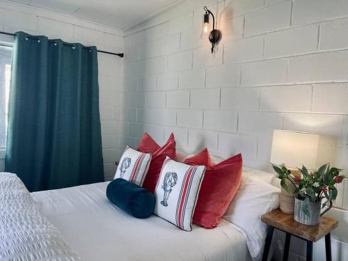 - une chambre avec un lit doté d'oreillers rouges et bleus dans l'établissement Barn Cottage Granite Belt Tiny Town Stay, à Wallangarra