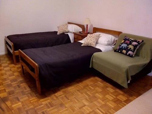 two beds and a chair in a room at Cortina in Buenos Aires