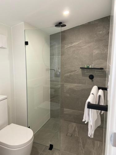 a bathroom with a shower with a toilet and towels at KI Seafront Holiday Park in Penneshaw