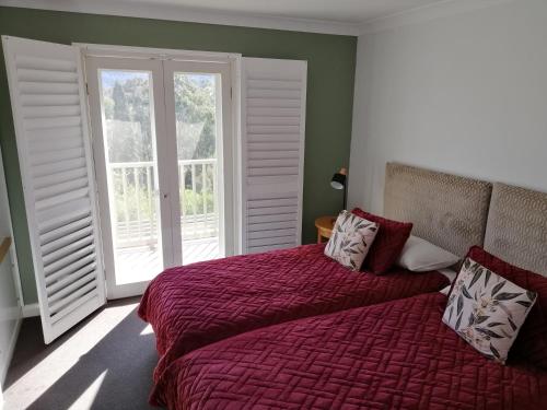 a bedroom with a bed and a large window at Cypress Lakes Villa Domenica in Pokolbin