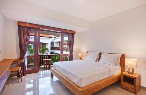 a bedroom with a large bed and a balcony at Sahadewa Suites Residence in Kerobokan