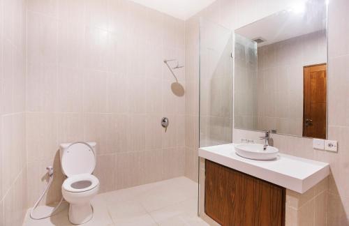 a bathroom with a toilet and a sink and a shower at Sahadewa Suites Residence in Kerobokan