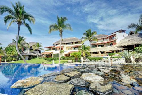 un complejo con piscina y palmeras en Las Palmas Luxury Villas, en Zihuatanejo