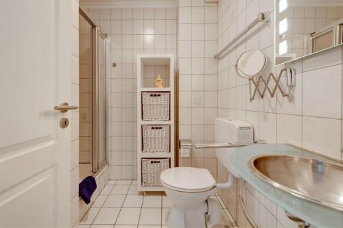 ein weißes Bad mit einem WC und einem Waschbecken in der Unterkunft Seeschlößchen Nr 4 in Büsumer Deichhausen