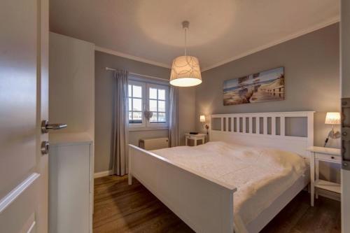 ein Schlafzimmer mit einem weißen Bett und einem Fenster in der Unterkunft Seeschlößchen Nr 4 in Büsumer Deichhausen