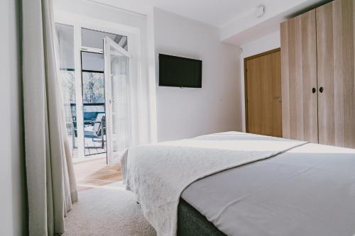a white bedroom with a bed and a television at ÖÖ Street Premium Apartment with Terrace in Tartu