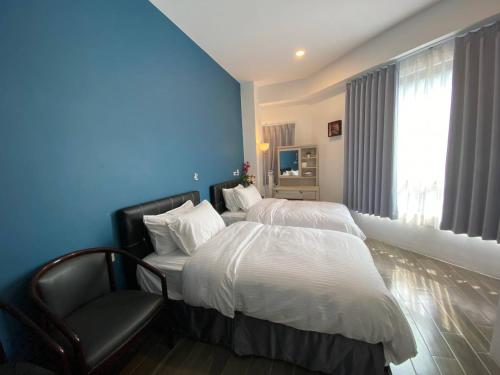 una habitación de hotel con 2 camas y una silla en Lukang Holiday Hostel, en Lukang