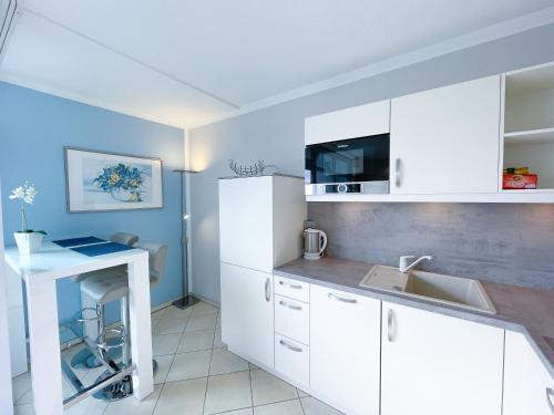 una cucina con mobili bianchi e un lavandino di Derzeit beliebt - Phänomenaler Ausblick auf Binnen- und Ostsee a Heiligenhafen