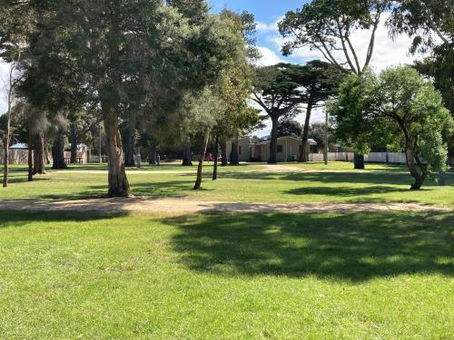 a park with green grass and trees and a building at Torquay Foreshore Caravan Park in Torquay