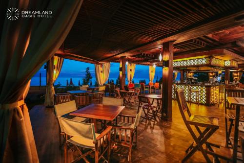 a restaurant with tables and chairs and a view of the ocean at Dreamland Oasis Hotel Chakvi in Chakvi
