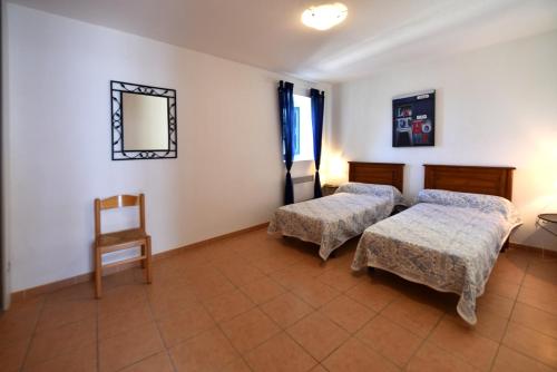 Cette chambre comprend deux lits, une chaise et un miroir. dans l'établissement GITE DU COUVENT-Scala, à Canari