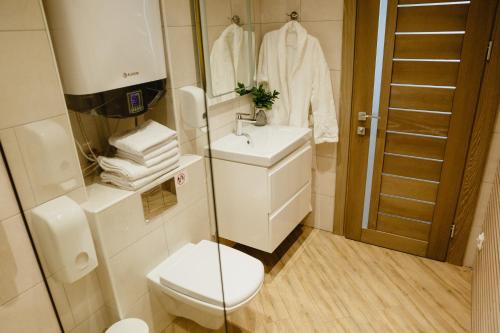a bathroom with a toilet and a sink and a mirror at Nicolas Resort Club in Kyiv