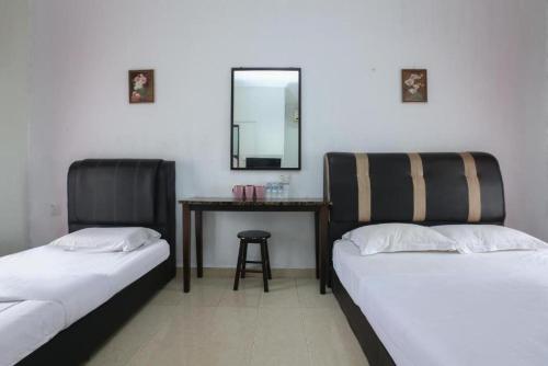 two beds in a room with a table and a mirror at Cerana Villa Eco Resort in Kota Bharu