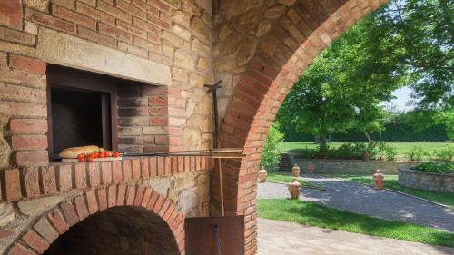 a brick wall with an oven in a yard at Villa Augusto 10, Emma Villas in Piegaro
