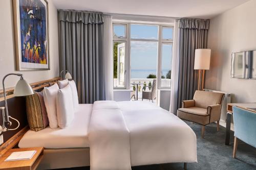 um quarto de hotel com uma cama grande e uma janela em Kurhotel Skodsborg em Skodsborg