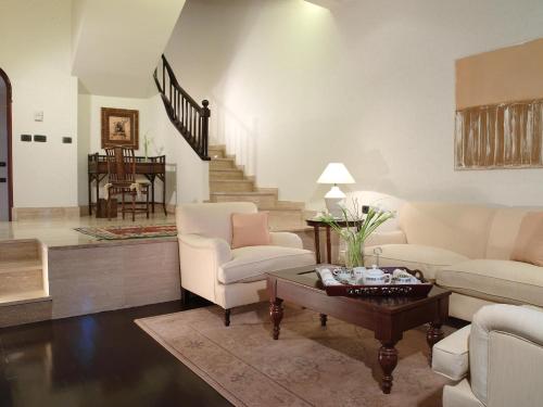 a living room with white furniture and a staircase at Hotel Las Madrigueras Golf Resort & Spa - Adults Only in Playa de las Americas