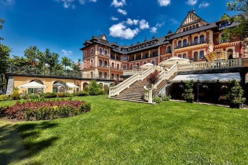 a large building with stairs in front of a yard at Grand Hotel Stamary in Zakopane