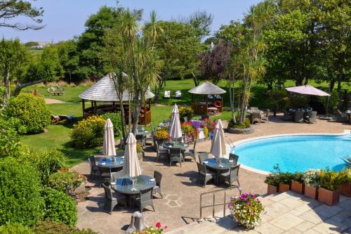 an outdoor patio with tables and chairs and a pool at The Farmhouse Hotel and Restaurant in St Saviour Guernsey