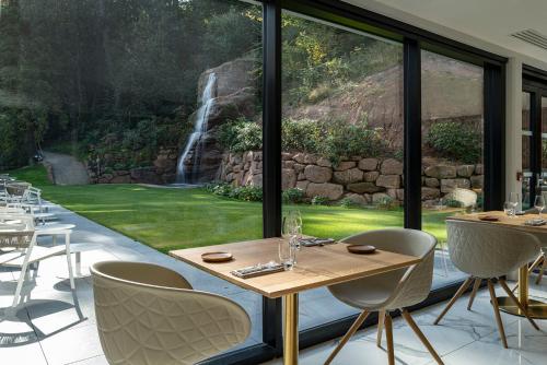 a restaurant with a waterfall seen through a large window at 6717 Nature Hôtel & Spa Le Clos des Délices in Ottrott